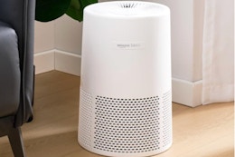 Amazon Basics Air Purifier for Home and Office sitting next to a couch on the floor.