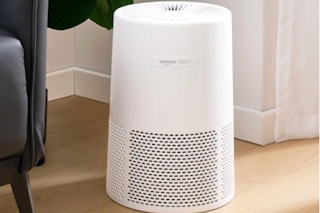 Amazon Basics Air Purifier for Home and Office sitting next to a couch on the floor.