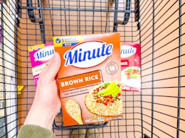 hand holding a box of minute rice over shopping cart