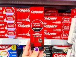 hand holding a box of Colgate-optic-white-pro-series-toothpaste in walmart aisle