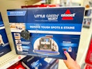 hand grabbing a bissell little green carpet cleaner off a target shelf