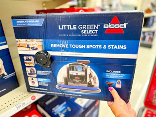 hand grabbing a bissell little green carpet cleaner off a target shelf