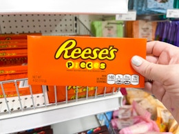 a hand holding a box of Reese's Pieces in a store