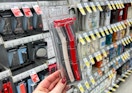 A hand holding Revlon dermaplaning razors in a store aisle