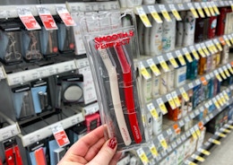 A hand holding Revlon dermaplaning razors in a store aisle