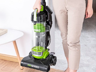 A person holding a Eureka Airspeed Vacuum in their home.