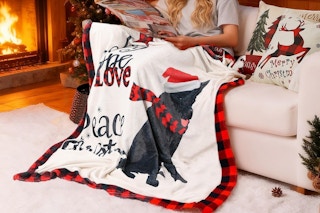 a woman sitting near a fireplace with a blanket