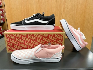 A variety of Vans shoes sitting on and surrounding a Vans box.