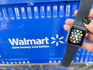 someone holding up an apple watch infront of a Walmart shopping basket