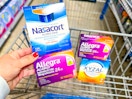 hand holding a box of Nasacort and Allegra in front of a cart with Xyzal and more Allegra