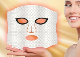 a person holding a red light face mask 