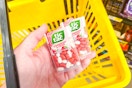 hand holding tic tac mints above yellow shopping basket