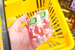 hand holding tic tac mints above yellow shopping basket
