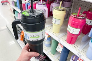 hand holding a reduce tumbler in front of a target shelf