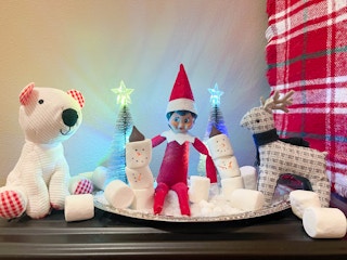 elf on the shelf doll next to marshmellow snowman next to studded animals 