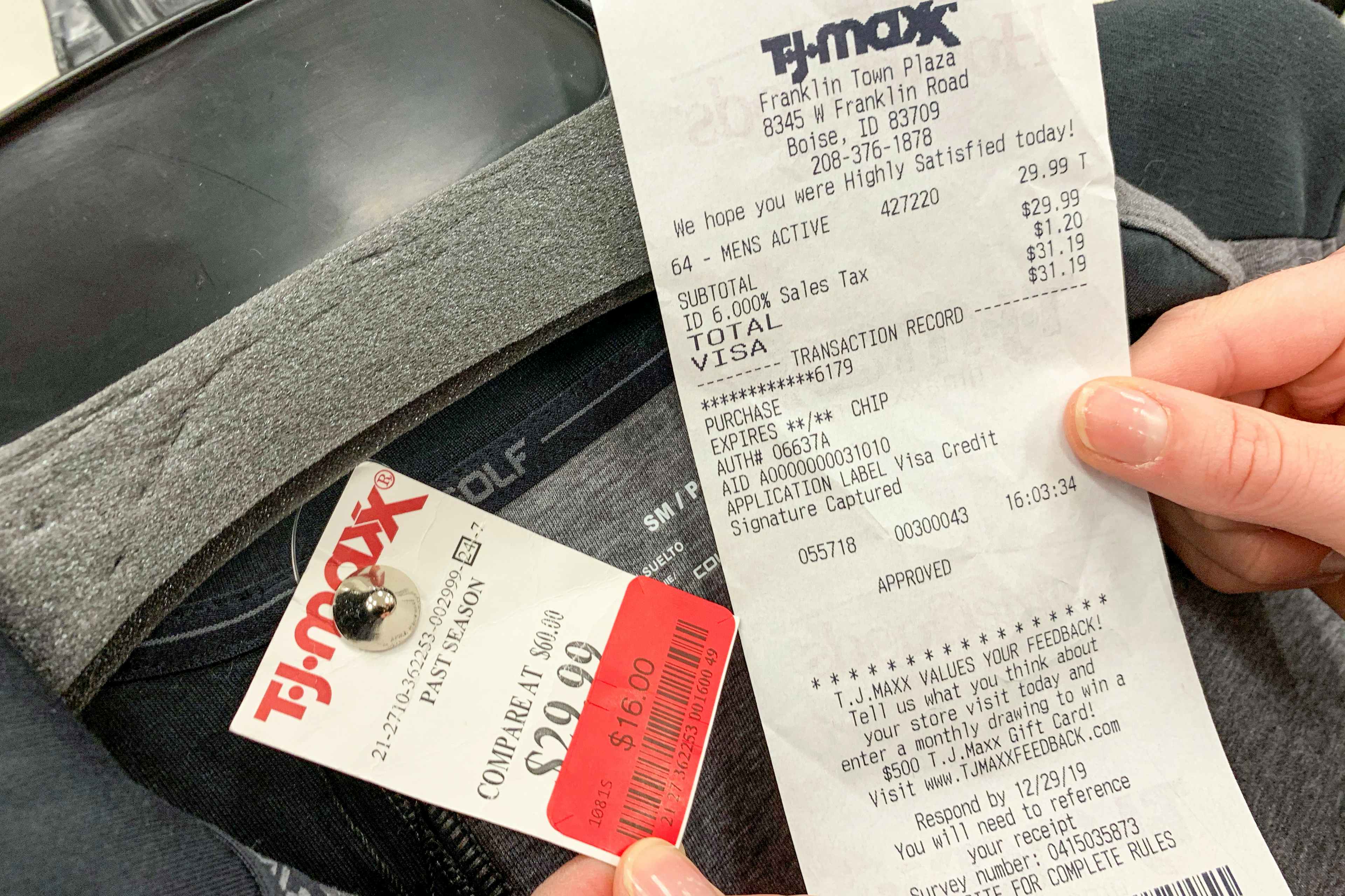 A receipt held next to a price tag with a red sales discount sticker on a sweater.