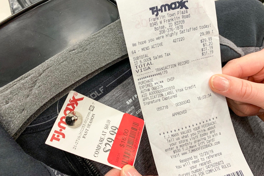 A receipt held next to a price tag with a red sales discount sticker on a sweater.