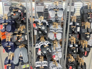 A store rack with a variety of nike slides hanging on it.