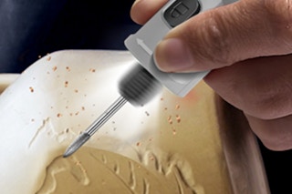 a rotary tool carving a design into a clay pot