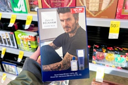 person holding a fragrance set in front of shelves