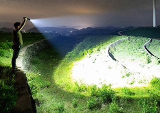 a person shining a flashlight in a grassy area