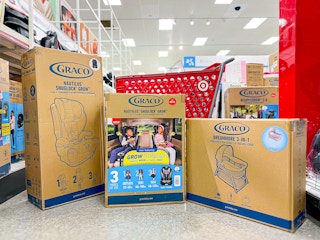 two car seats and a bassinet on the floor at Target in front of a Target cart