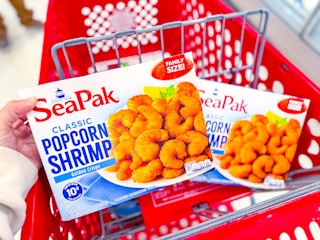 hand holding sea pak frozen shrimp family pack over a target cart