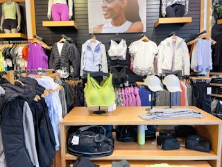 A variety of workout apparel hanging on store racks and sitting on store tables.