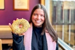 a person holding up a bagel while smiling