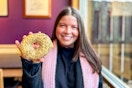 a person holding up a bagel while smiling