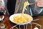 a person grabbing olive garden pasta with a fork