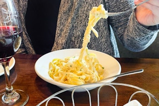 a person grabbing olive garden pasta with a fork