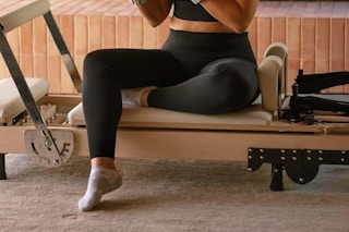 The bottom half of a woman who just finished working out, wearing a pair of black full-length stretch leggings.
