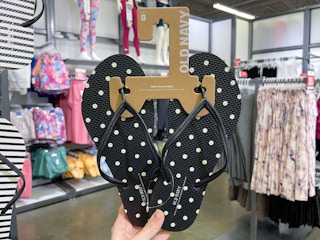 hand holding up a pair of polka dot flip flops