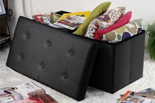 black faux leather ottoman with pillows and magazines inside