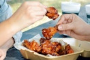 two people sharing a box of Wingstop chicken wings