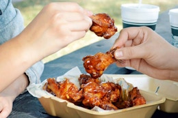 two people sharing a box of Wingstop chicken wings