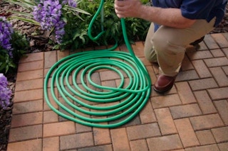 a man watering his yard with the Lizard Expandable Hose