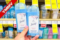 person holding 2 secret deodorants in front of a shelf