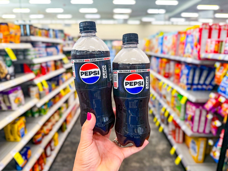 person holding 2 pepsi zero sugar sodas in an aisle