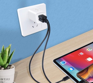 a device on a table plugged into an outlet on a blue wall
