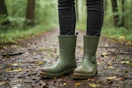 lifestyle image of a person wearing green rain boots outside on a trail