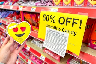 hand holding an emoji heart eyes box next to a clearance sign for 50% off candy