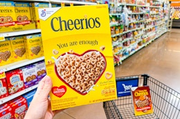 hand holding a box of general mills cereal