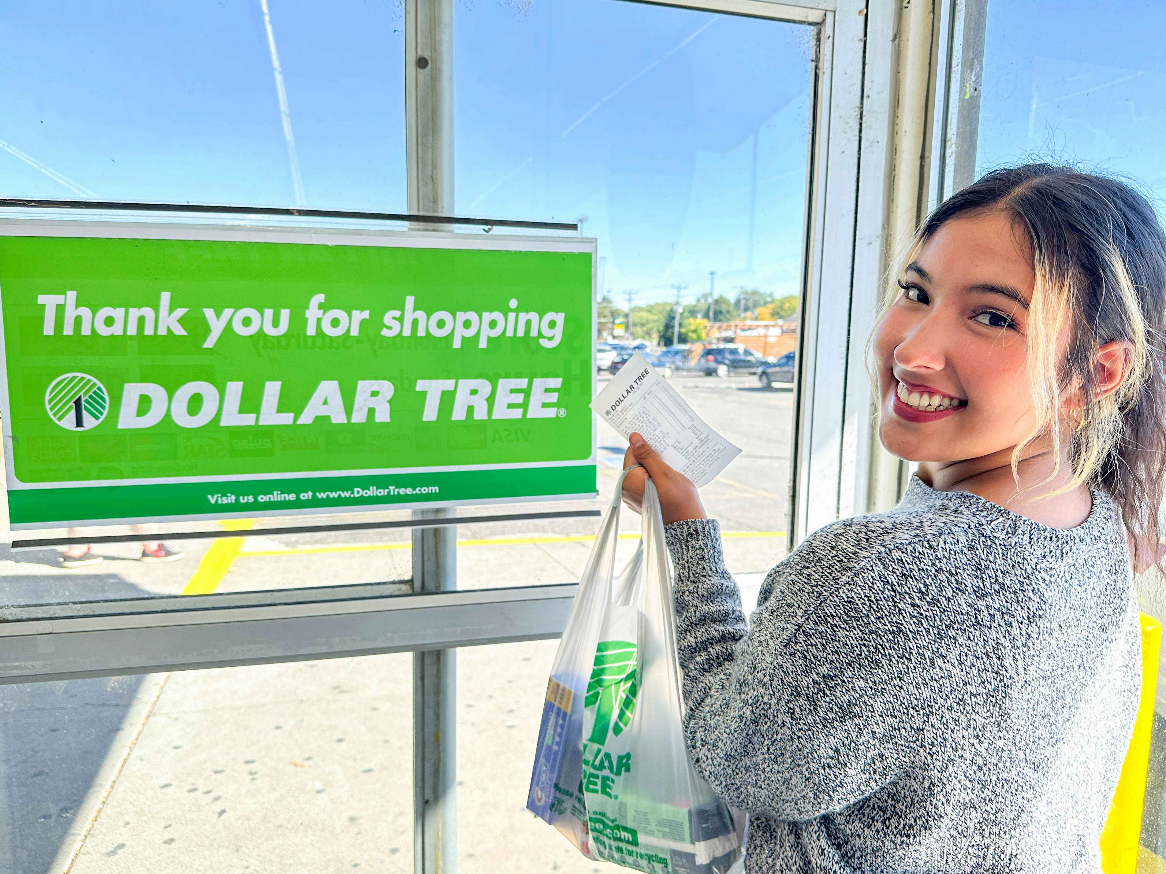 a woman smiling holding her dollar tree bag and receipt in store 