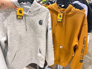 Yellow and hand holding up grey Carhartt Hoodie