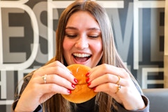 a person taking a bite of a mcdonalds hamburger