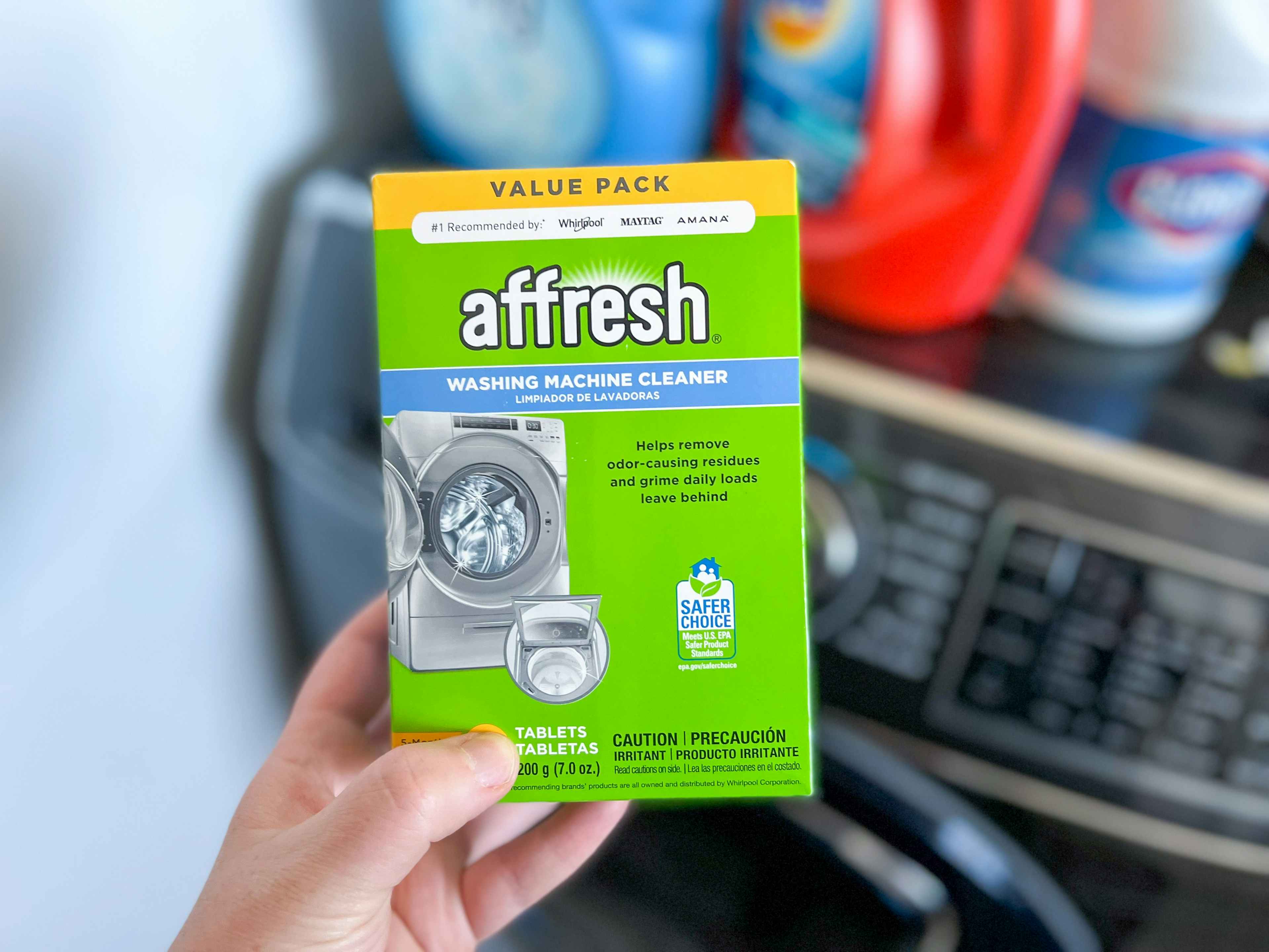 someone holding affresh washing machine cleaner in front of washing machine