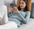 a woman on a couch charging her phone