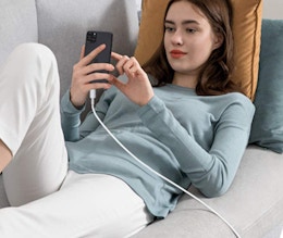 a woman on a couch charging her phone